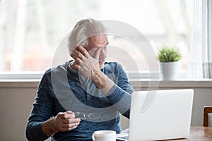 Fatigued mature man taking off glasses suffering from tired eyes