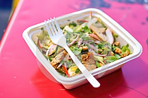 fattoush in a takeaway container, with a fork on the side