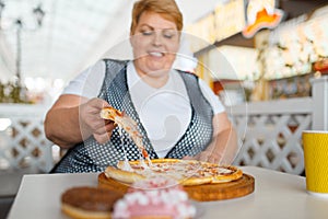 Fatty woman eating pizza in fastfood restaurant