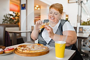 Fatty woman eating pizza in fastfood restaurant