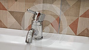 Faucet in the bathroom with running water. Man constantly turns off the water to conserve water energy and protect the