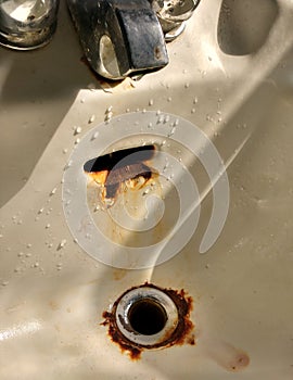 Faucet Dripping in a Porcelain Sink with Rusty Drain