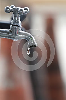 Faucet dripping water drop