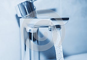 Faucet and flowing water on blue background