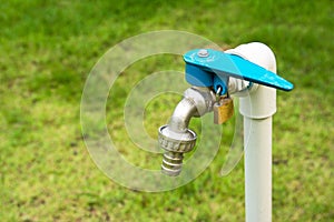 Faucet with key lock with grass field background