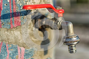 Faucet on Old Blue Painted Wall. Red Handle Water Tap Outdoor Background. Save Water Concept.
