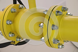 Faucet on the pipeline, large steel nuts. Close-up of a yellow gas pipe with nuts and bolts.