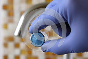 Faucet with scum. Gloved hand holding aerator, close-up