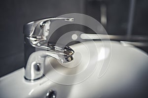 Faucet and water drop close up. Bathroom interior with sink and water tap.