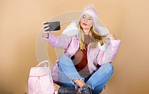 Faux fur fashion. warm winter clothing. phone selfie. flu and cold season. Leather bag fashion. woman in beanie hat with