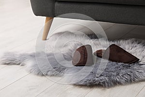 Faux fur rug with slippers on floor in room