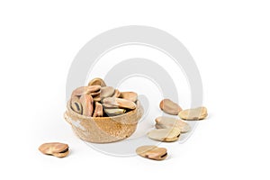 Fava beans scattered around a ceramic bowl isolated over white