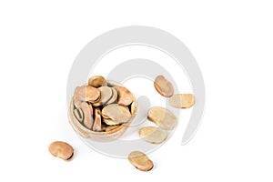 Fava beans scattered around a ceramic bowl isolated over white top down view