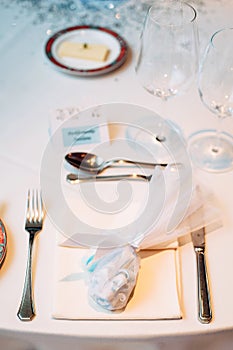 Favor idea. Small preset for guests on a plate, wineglasses and cutlery on table photo