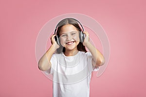 Favorite music and device. Happy little girl baby holds on headphones on head
