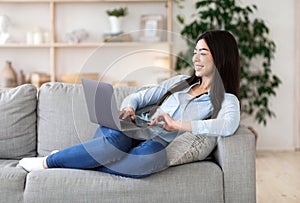 Favorite Pastime. Cheerful Asian Woman Relaxing With Laptop On Couch, Browsing Internet