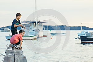 Fazana, Croatia - June 1, 2019: two little boys fishing at sea wooden pier. sea dock