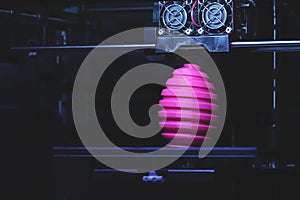 FDM 3D-printer manufacturing wound pink easter egg sculpture - front view on object and print head