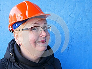 Feamle Engineer in the construction helmet on blue background, closeup