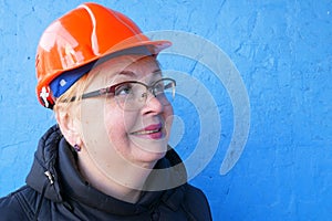 Feamle Engineer in the construction helmet on blue background, closeup