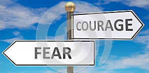 Fear and courage as different choices in life - pictured as words Fear, courage on road signs pointing at opposite ways to show