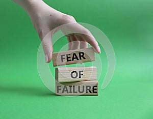 Fear of failure symbol. Concept words Fear of failure on wooden blocks. Beautiful green background. Businessman hand. Business and