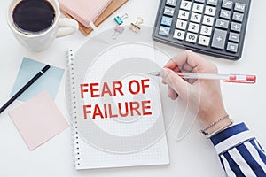 FEAR OF FAILURE word on a notepad with clipboard , chart and calculator, business concept