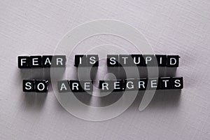 Fear is stupid so are regrets on wooden blocks. Motivation and inspiration concept