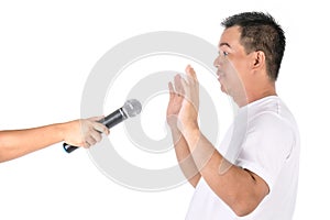 Fear to speak concept. Man show his hand to avoid microphone in studio. Isolated on white