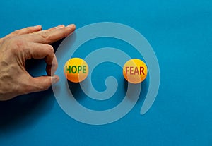 Fear vs hope symbol. Male hand is about to flick the ball. Orange table tennis balls with words fear and hope. Beautiful blue