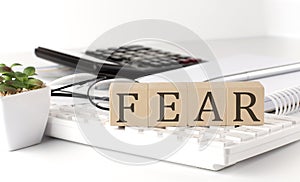 FEAR written on a wooden cube on keyboard with office tools