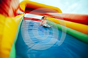 Scared Little Girl Playing on an Inflatable Slide in Amusement Park photo