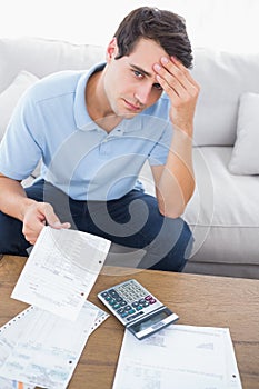 Fearful man doing his accounts with a calculator