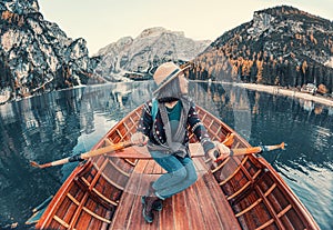 Fearless Asian traveler sails in a boat on a beautiful high mountain lake at autumn time