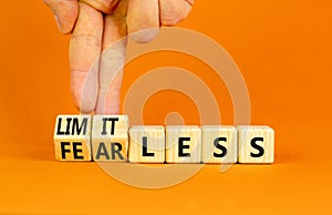 Fearless and limitless symbol. Concept word Fearless and limitless on wooden cubes. Businessman hand. Beautiful orange table