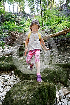 Fearless little girl scout jumping over stones