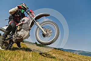 A fearless professional motocross rider skillfully executes an extreme back wheelie maneuver through a perilous forest