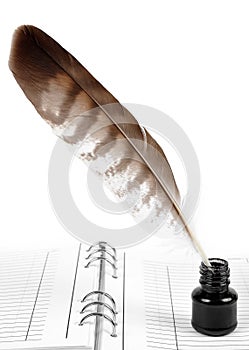 Feather with ink bottle and workbook photo