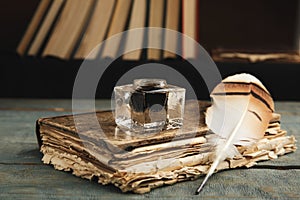 Feather pen, inkwell and book on blue wooden table