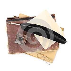 Feather pen, inkwell and old books on white background, top view