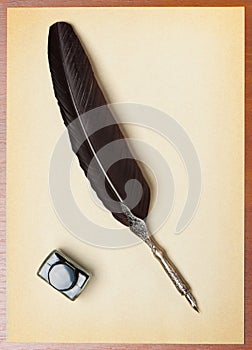 Feather quill and inkwell on an old paper photo