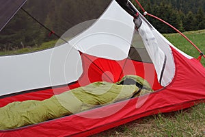 Feather sleeping bag in open inner tent body without rainfly, on mountain col in grass in the morning. Mala Fatra mountains,