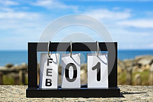 Feb 01 calendar date text on wooden frame with blurred background of ocean