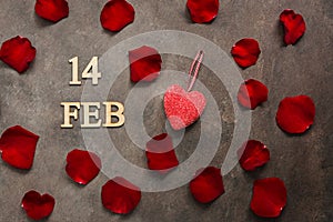FEB 14, Valentine`s Day. Red rose petals and heart on adark brown rustic background. Top view, flat lay