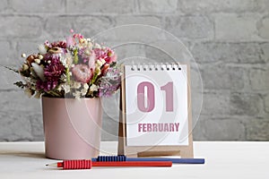 february 01. 01-th day of the month, calendar date.A delicate bouquet of flowers in a pink vase, two pencils and a