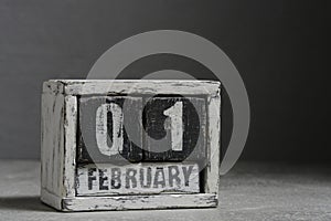 February 01 on wooden calendar, on dark gray background.