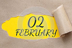 february 02. 02th day of the month, calendar date.Hole in paper with edges torn off. Yellow background is visible