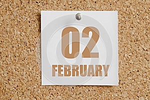 february 02. 02th day of the month, calendar date.White calendar sheet attached to brown cork board.Winter month, day of