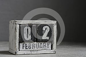 February 02 on wooden calendar, on dark gray background.