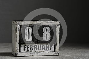 February 08 on wooden calendar, on dark gray background.